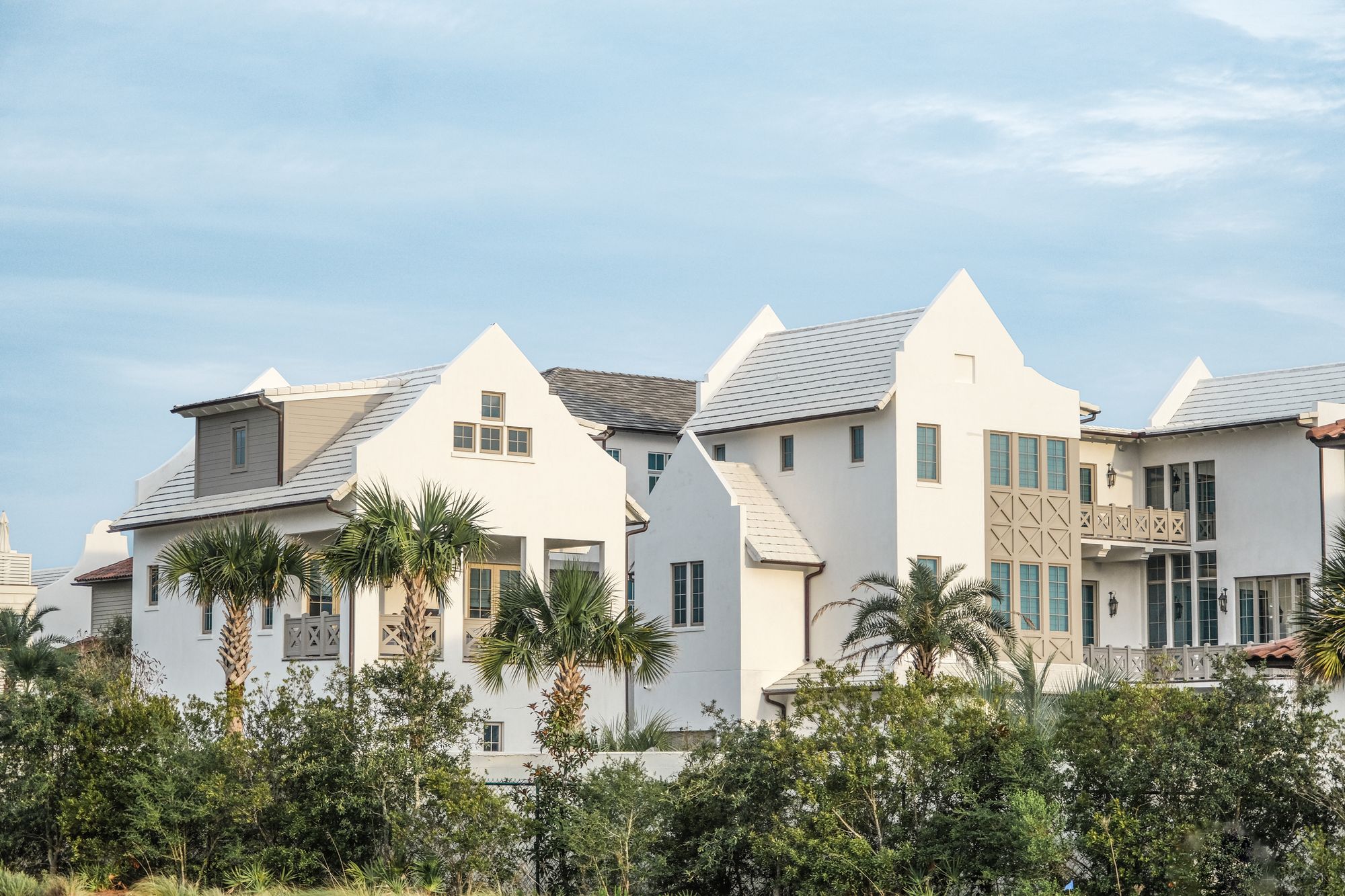 White limestone Palm Beach residence behind clipped hedges in early morning light